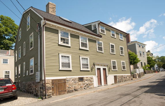 Front view of a multi-story house with a stone foundation and green siding.