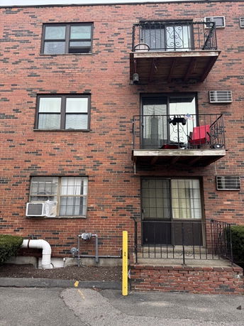 Front view of a brick apartment building with balconies and windows.