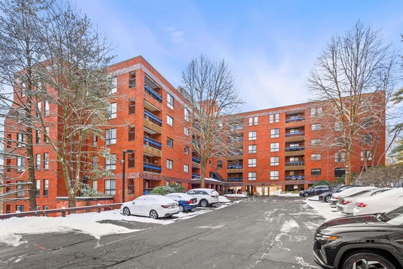 Front view of a multi-story brick apartment building with balconies.