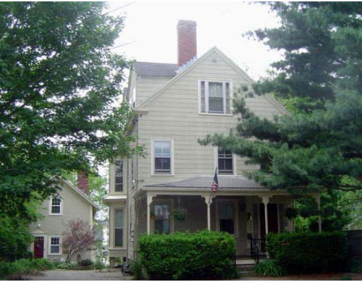 Front view of a two-story house with a porch and a chimney.