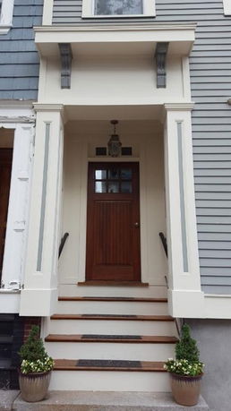 Front view of a house entrance with steps leading to a wooden door.