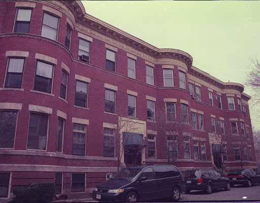Front view of a multi-story brick building with multiple windows and curved sections.