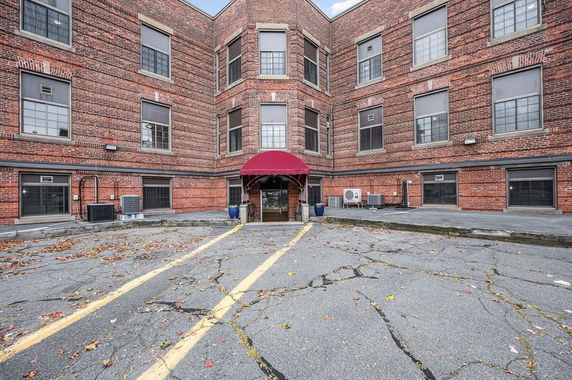 Exterior view of a multi-story brick building with large windows and a red canopy over the entrance.