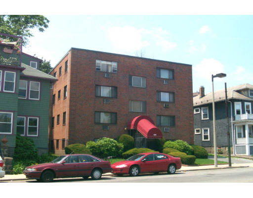 Front view of a three-story brick apartment building with a red awning.