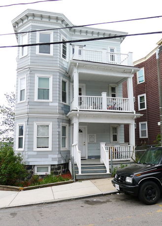 Front view of a three-story house with balconies on each floor.