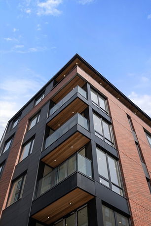 Front view of a modern multi-story building with large windows and balconies.