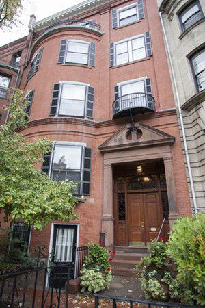 Front view of a multi-story brick building with large windows and a main entrance door.