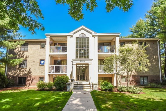 Front view of a three-story residential building with balconies and a central glass entrance.