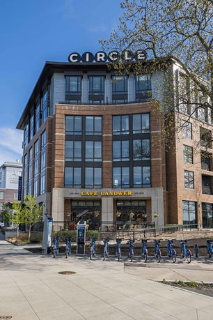 Front view of a multi-story brick building with large windows and a cafe on the ground floor.