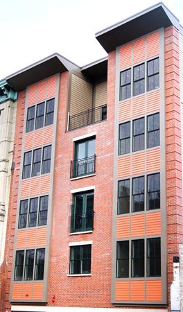 Front view of a multi-story brick residential building with large windows.