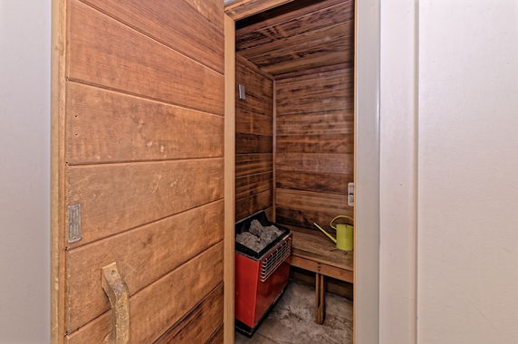 Interior view of a wooden sauna room with a bench and heater.