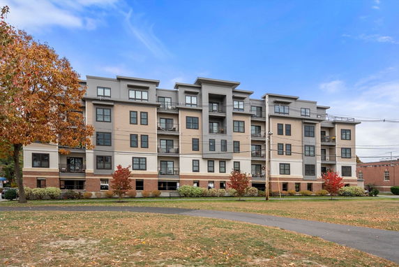 Front view of a multi-story apartment building with balconies and brick accents.