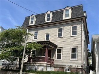 Front view of a multi-story house with a porch and dormer windows.