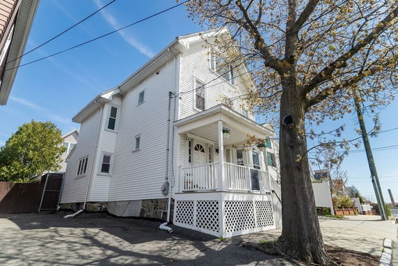 Front and side view of a two-story house with a porch and white siding.