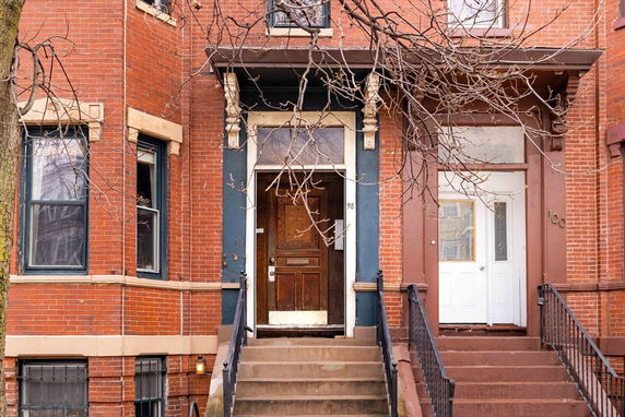 Front view of a multi-story brick building with two entrances and staircases.