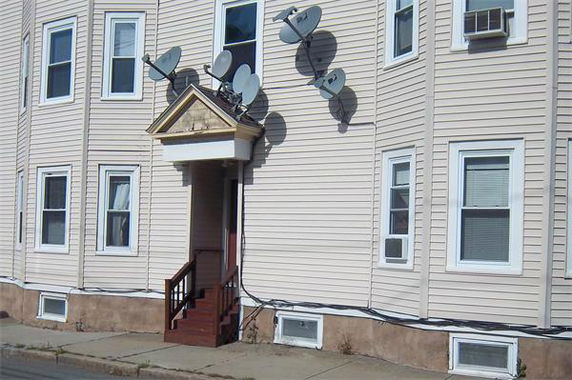Front view of a building with multiple satellite dishes attached.