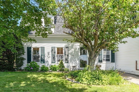 Front view of a house with white siding and green shutters.