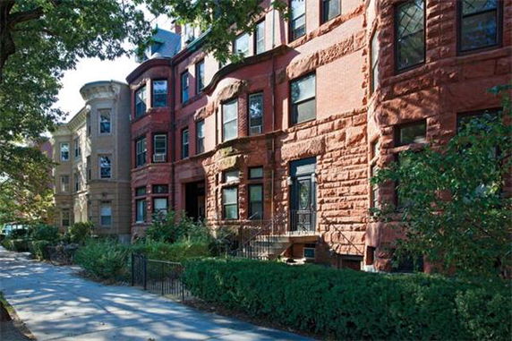 Front view of a row of historic multi-story brick townhouses with ornate architectural details.