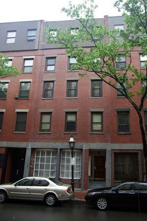 Front view of a multi-story brick building with several windows.