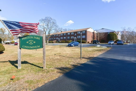 Front view of a condominium building with parking area in front.