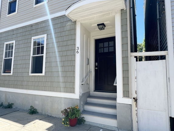 Front view of a building entrance with steps leading to a black door.
