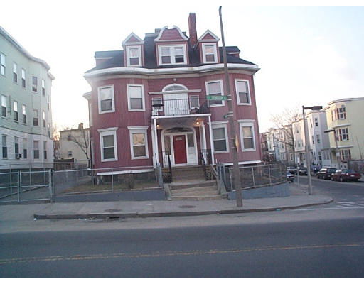 Front view of a multi-story building with a red facade and multiple dormer windows.