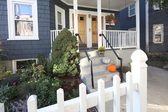 Front view of a two-story house with a porch and stairs.