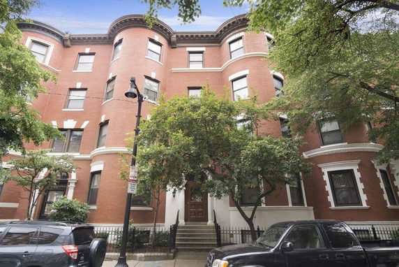 Front view of a multi-story brick building with rounded bay windows.