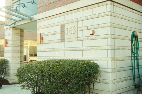 Front view of a building with a brick and stone exterior and the number 163 displayed.