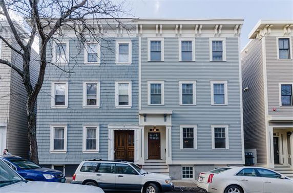 Front view of a three-story residential building with a light blue exterior and white trim.