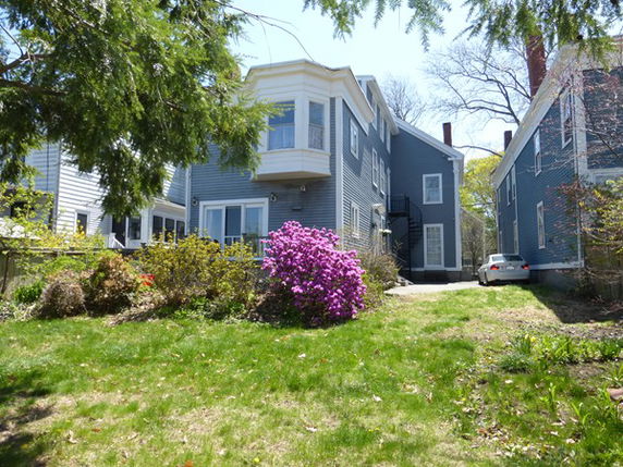 Front view of a two-story house with blue siding and a bay window.