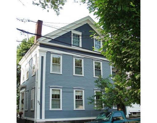 Front view of a multi-story blue house with white trim and a chimney.