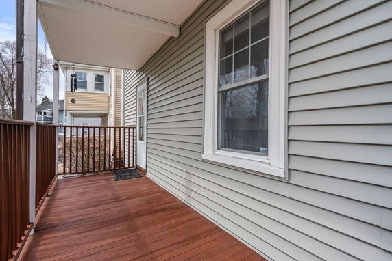 Front view of a house with a small porch and wooden railing.
