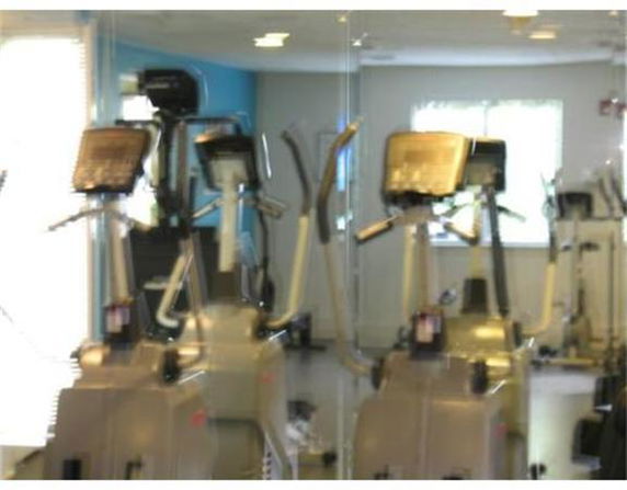 Indoor gym area with exercise equipment and mirrors on the wall.
