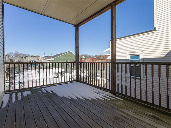 View of residential area from a wooden deck with some snow on the floor.