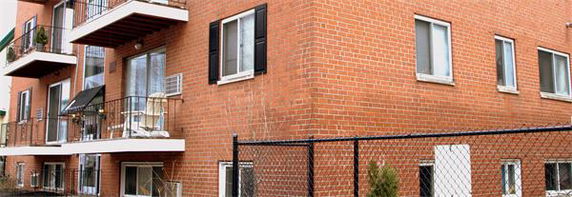 Front view of a multi-story brick apartment building with balconies.