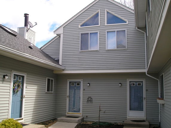 Front view of a house with multiple doors and a triangular upper window feature.