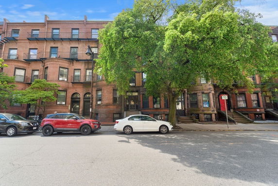 Front view of a multi-story brick building with arched windows and fire escapes.