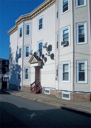 Front view of a multi-story building with multiple satellite dishes attached.