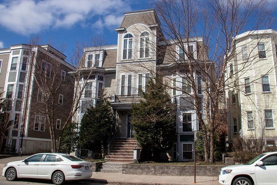 Front view of a multi-story house with a central gable roof and arched windows.