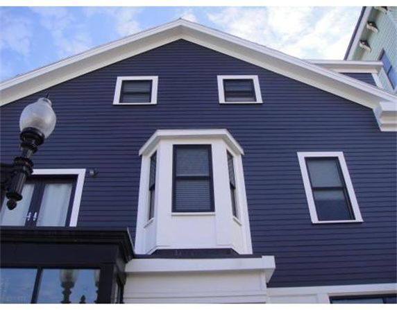 Front view of a house with dark blue siding and multiple windows.