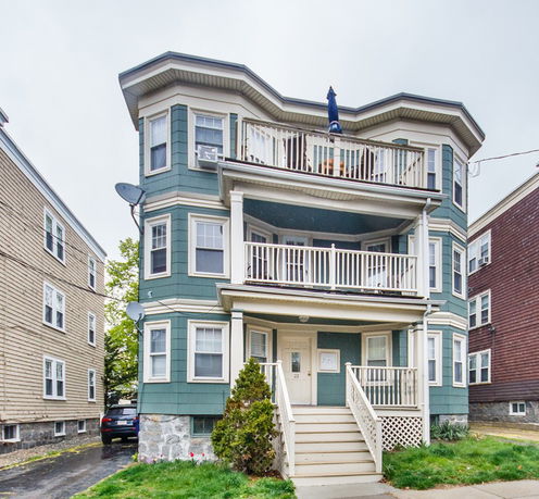 Front view of a multi-story house with multiple balconies and a central entrance.