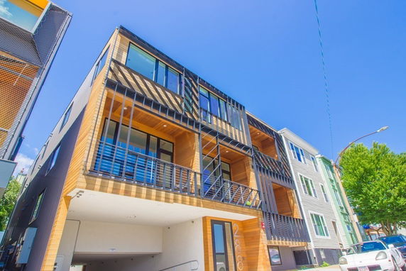 Front view of a modern multi-story building with wooden accents and balconies.