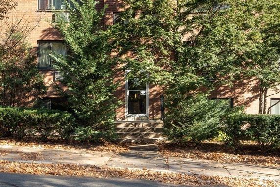 Front view of a building with brick exterior partially obscured by trees.