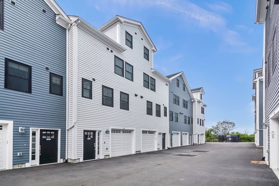 Front view of a row of multi-story townhouses with garages.