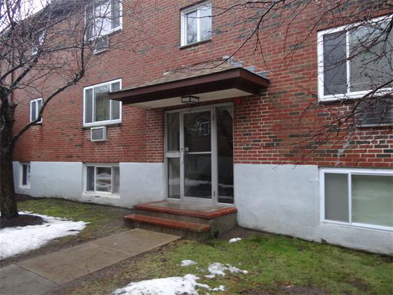 Front view of a multi-story brick house with a main entrance and several windows.