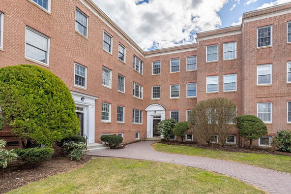 Front view of a brick apartment building with multiple windows.