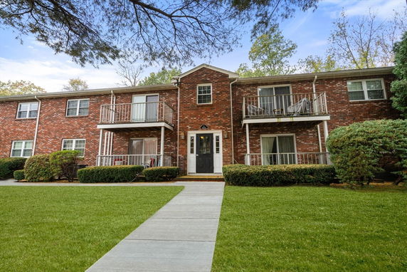 Front view of a two-story brick apartment building with balconies.