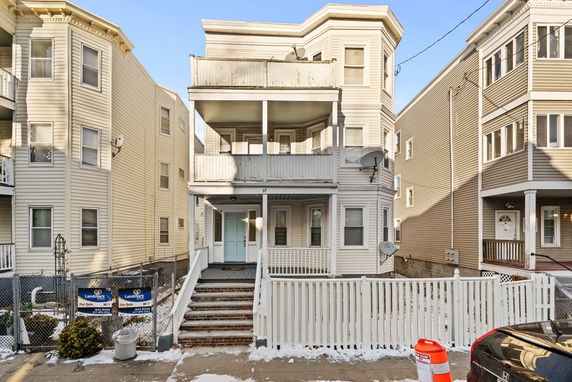 Front view of a multi-story residential building with a porch and balcony.