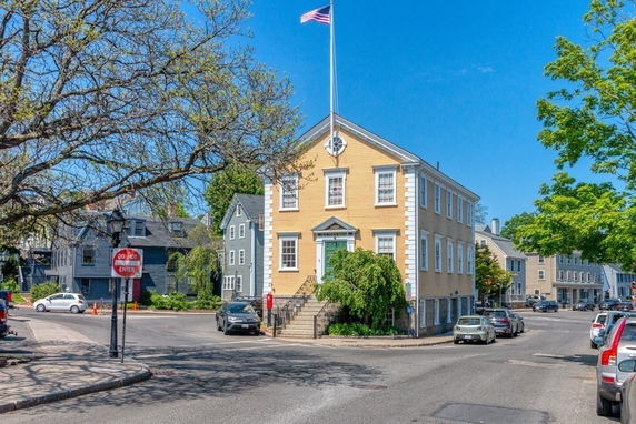 Front view of a two-story corner building with a flagpole on top.